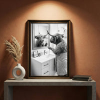 A crisp black and white photograph of a Highland cow looking in a bathroom mirror and holding a razor, with a small sign that says IT'S A PROCESS, created by Artazyn.