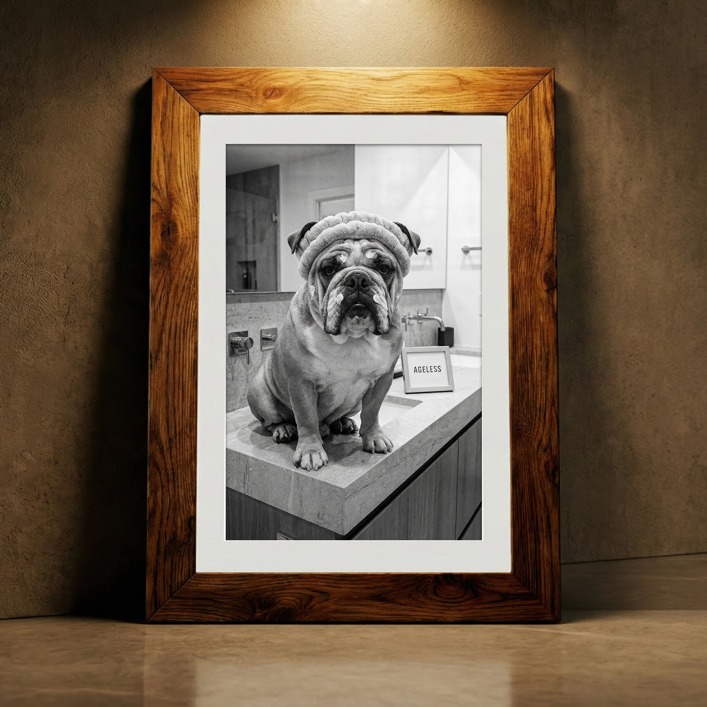 A crisp black and white photograph of a bulldog sitting on a marble bathroom counter wearing a spa headband and face cream next to a sign that says AGELESS, created by Artazyn.