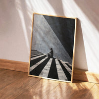 High-contrast black and white illustration of a figure sitting on striped steps with dramatic geometric shadows.