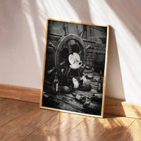 Framed artwork of a character sitting at a ship's wheel with bottles on a wooden floor.
